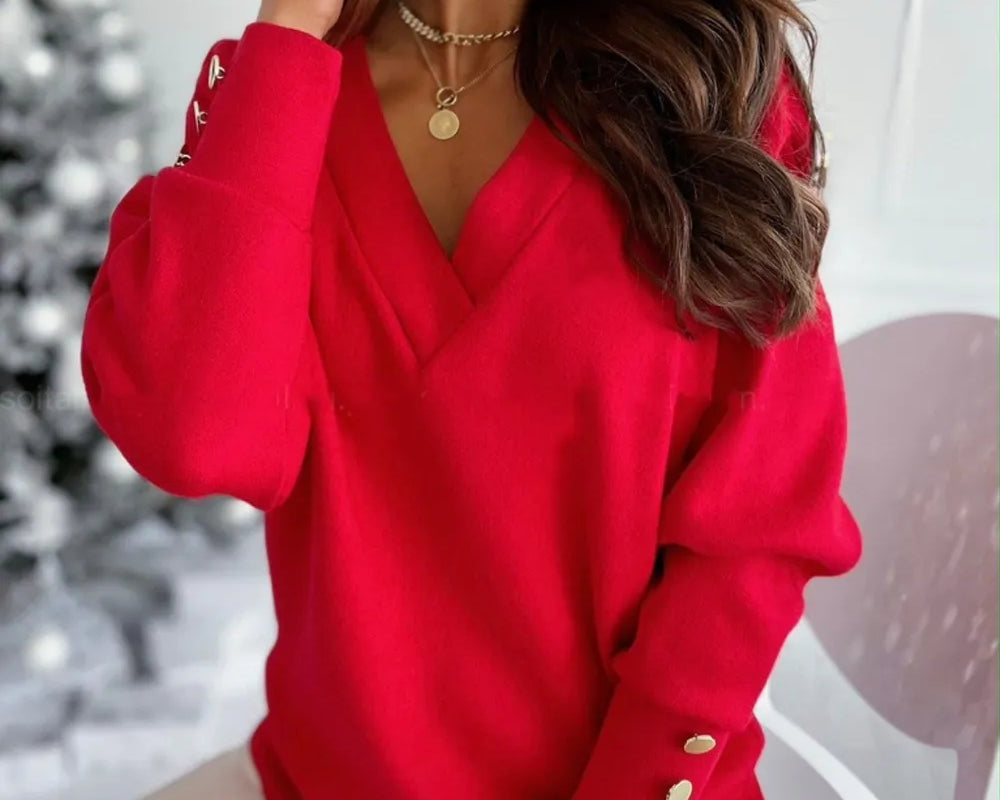 NEWYORKLISTED STYLE COLLECTION: Woman wearing a red sweater with gold buttons in a blurred indoor setting