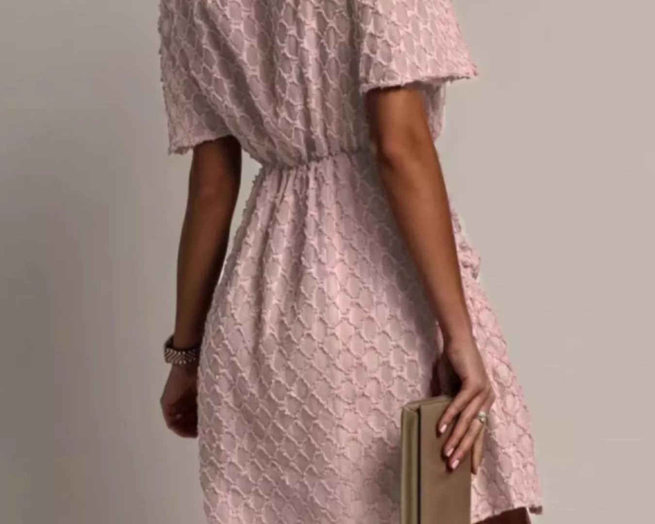 NEWYORKLISTED STYLE COLLECTION: Woman wearing a pink lace dress holding a book against a plain background