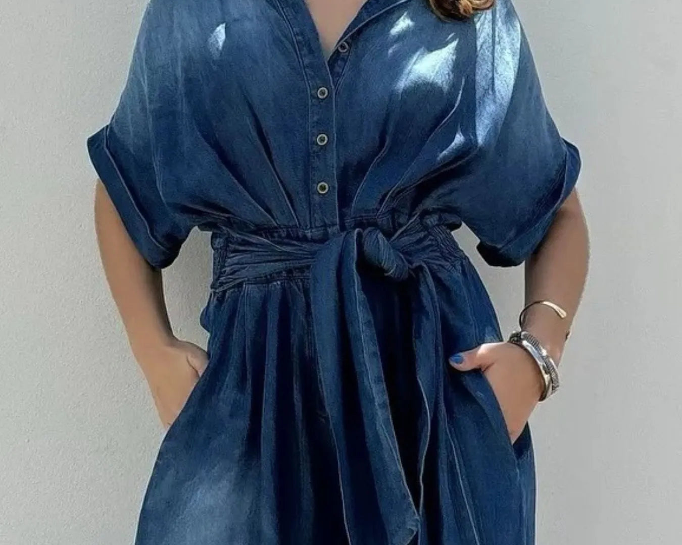 NEWYORKLISTED STYLE COLLECTION: Woman wearing a blue denim dress against a plain background