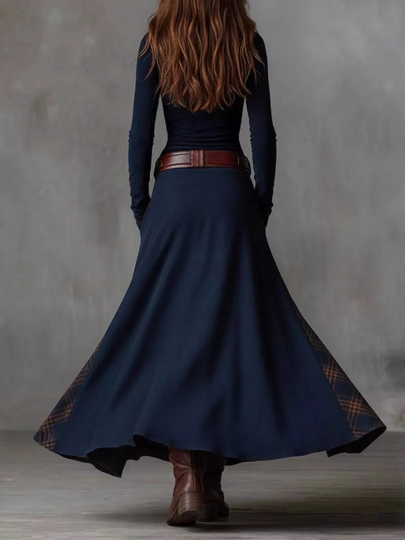 NEWYORKLISTED Style Collection: Person wearing a long navy dress with a belt and brown boots against a gray background