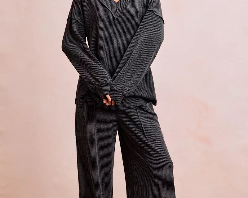 NEWYORKLISTED Comfort Collection: Woman wearing a dark gray outfit with wide-leg pants on a plain background