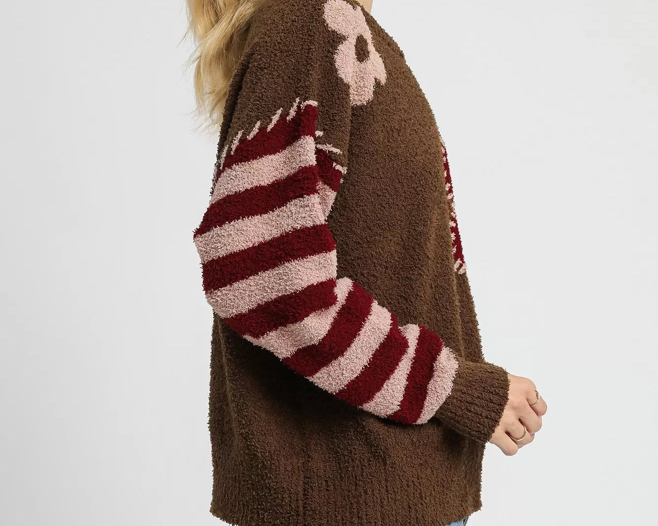 NEWYORKLISTED STYLE COLLECTION: Woman wearing a brown sweater with red and white striped sleeves on a white background