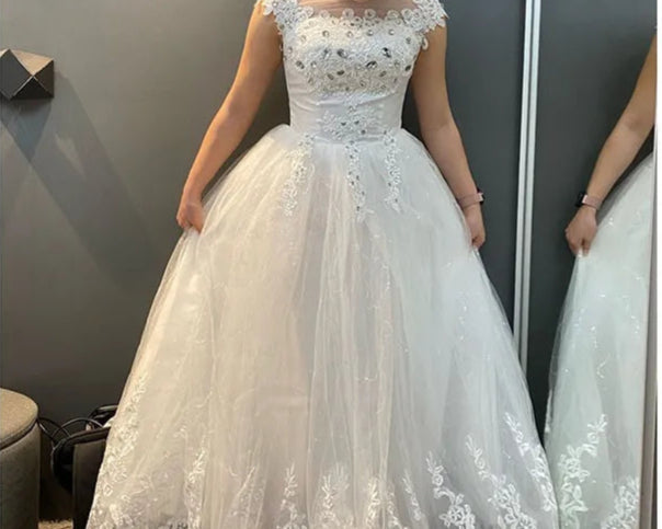 Woman wearing a white lace wedding dress in front of a mirror.