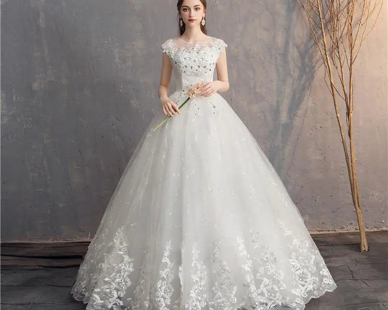 White lace wedding dress on a model against a textured wall.