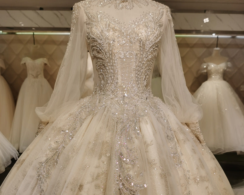 Regal long-sleeve ball gown wedding dress with illusion neckline, shimmering embroidery, and dramatic long train, NEWYORKLISTED ELEGANT BRIDE COLLECTION.