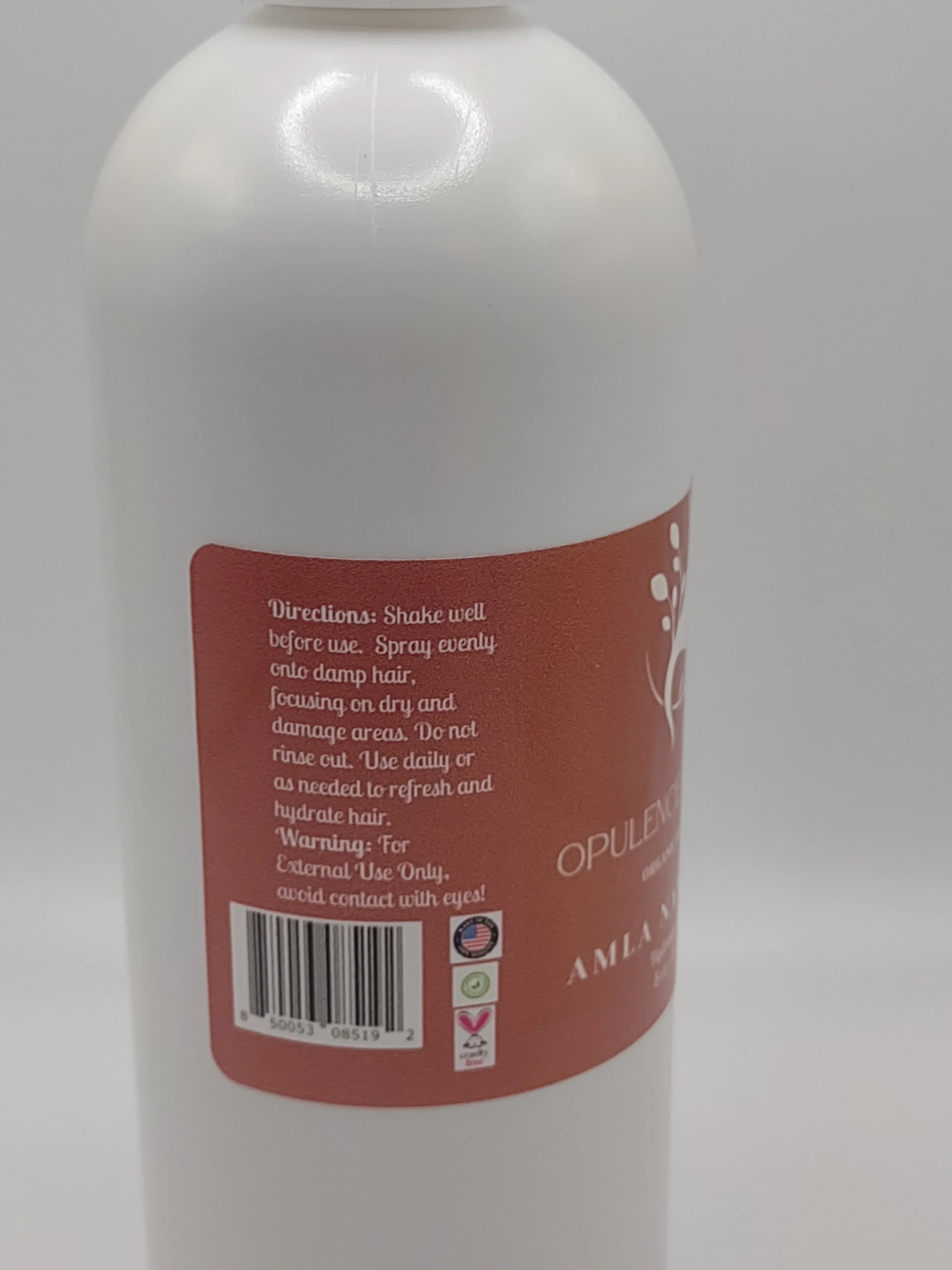 Close-up of a bottle label with text and a barcode on a white background: AMLA NATURALS - Opulent Hair Nourishment Mist