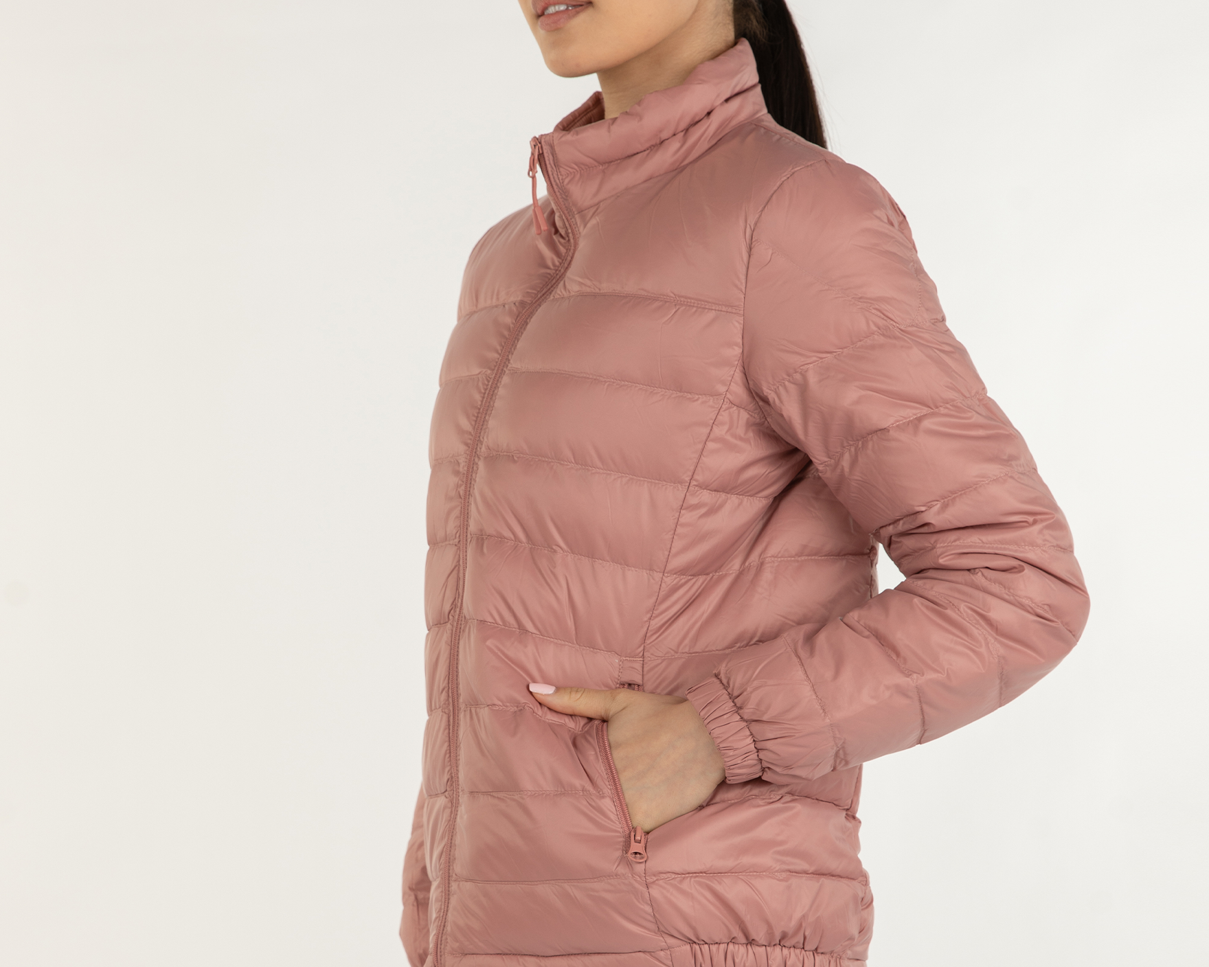 Woman wearing a pink puffer jacket on a white background