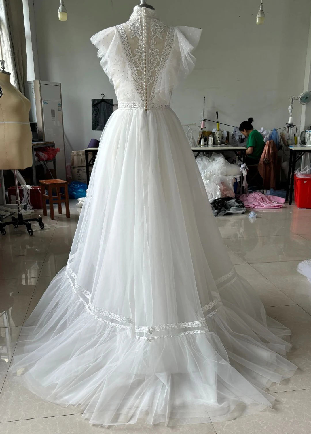 White wedding dress on a mannequin in a workshop setting