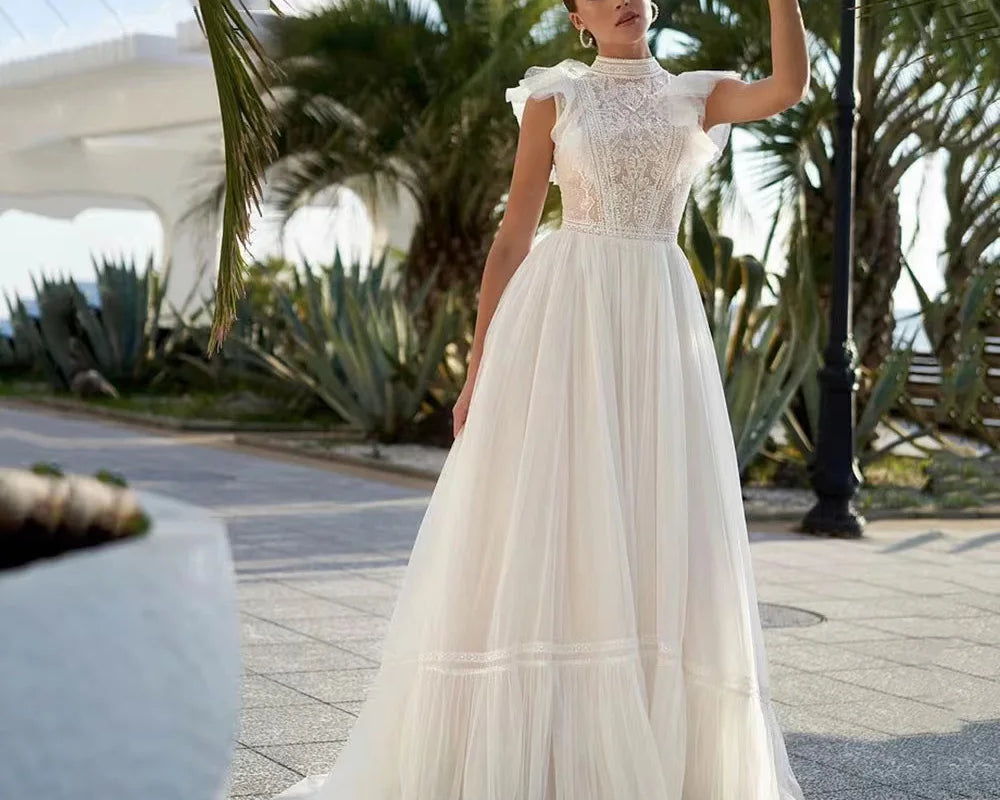 Customizable sleeveless A-line wedding dress with sheer tulle, lace detailing, high neckline, and court train from NEWYORKLISTED Elegant Bride Collection.