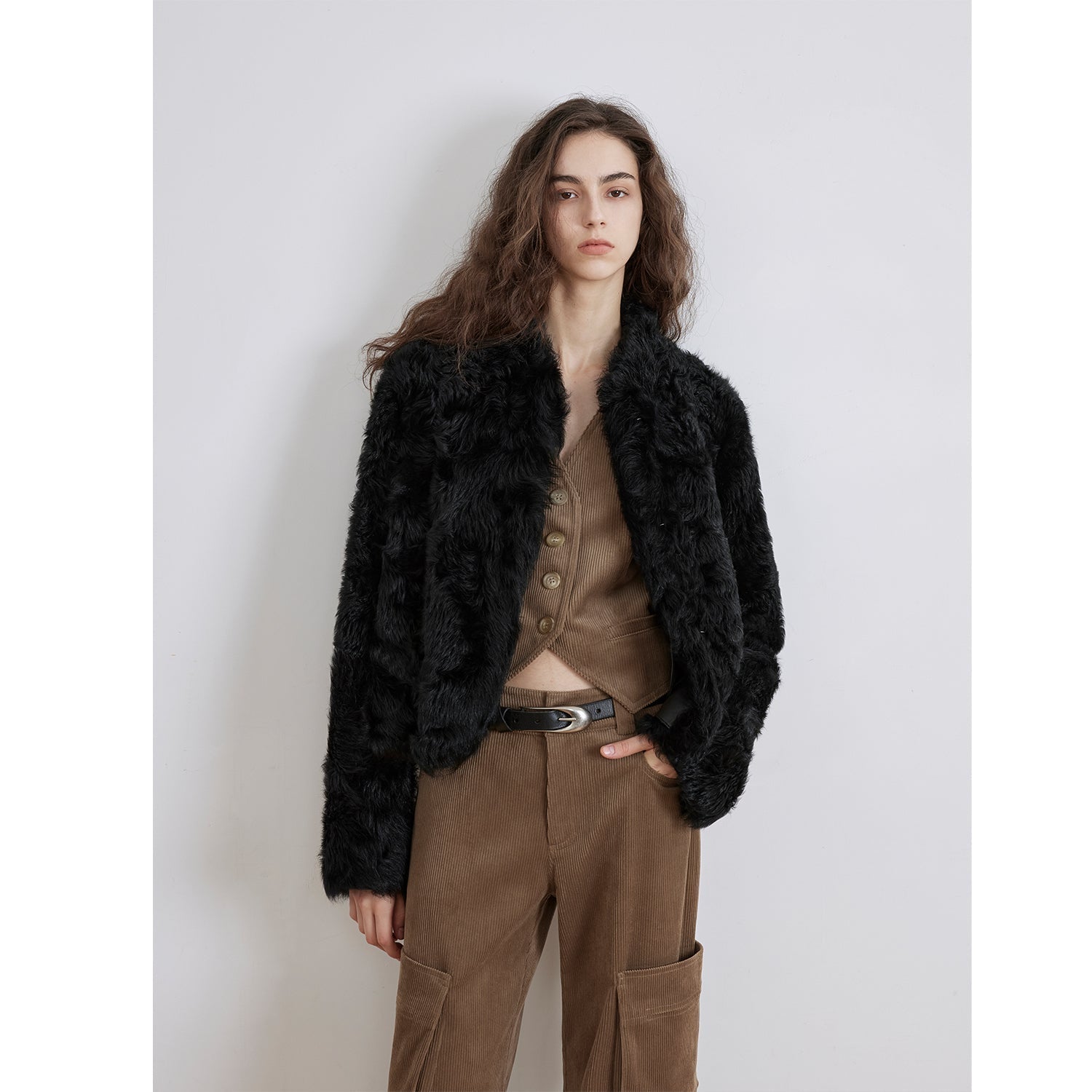 NEWYORKLISTED STYLE COLLECTION: Person wearing a black fur jacket and brown pants against a white background