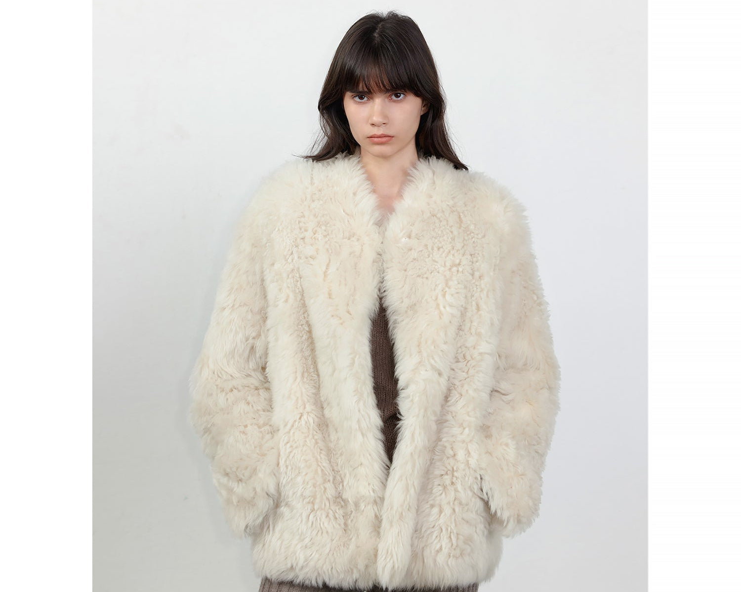 NEWYORKLISTED STYLE COLLECTION: Person wearing a fluffy white coat against a plain background