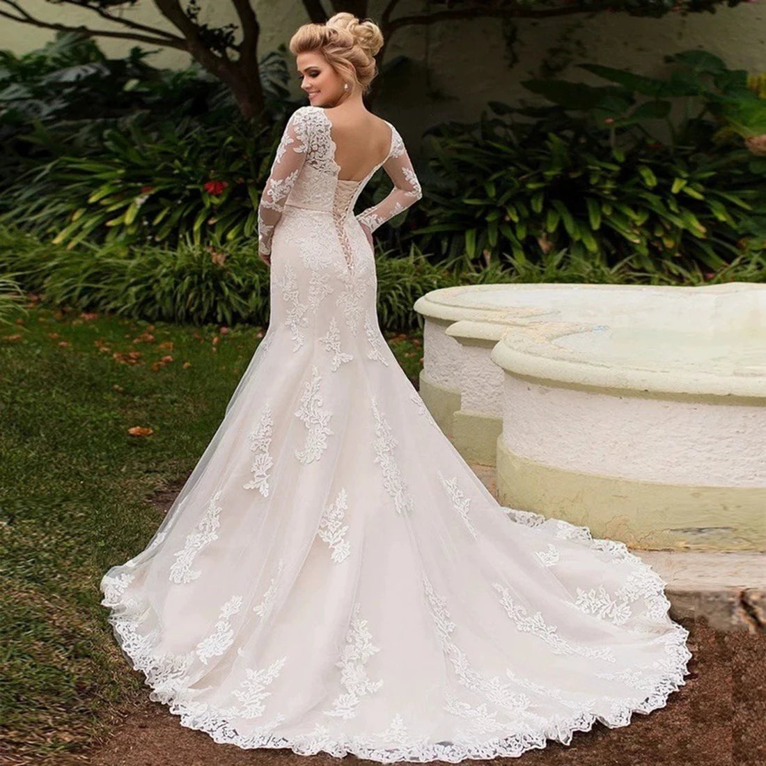 Woman wearing a white lace wedding dress in an outdoor setting.