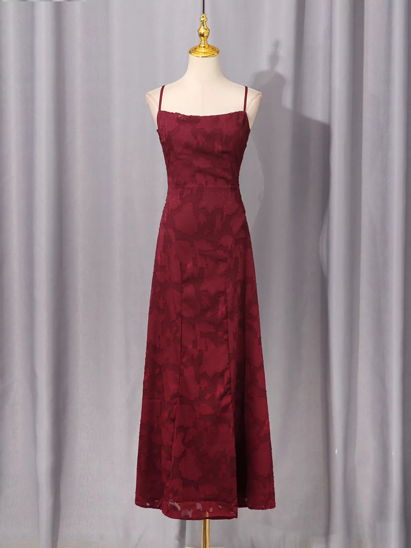 NEWYORKLISTED STYLE COLLECTION: Burgundy dress on a mannequin against a gray curtain background
