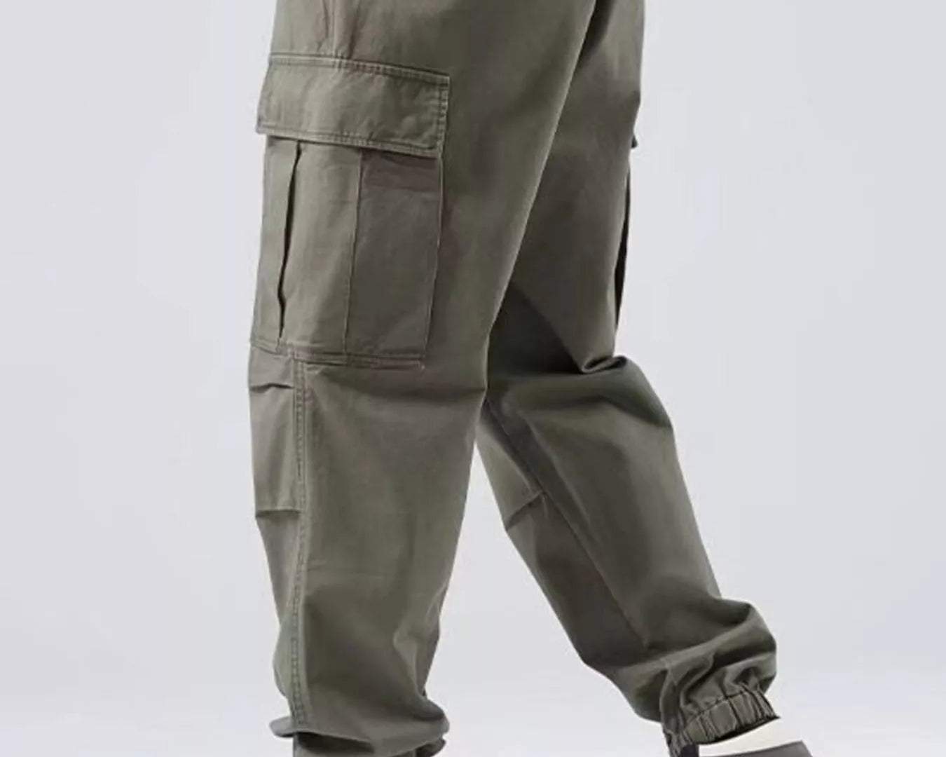 Person wearing olive green cargo pants with a plain background