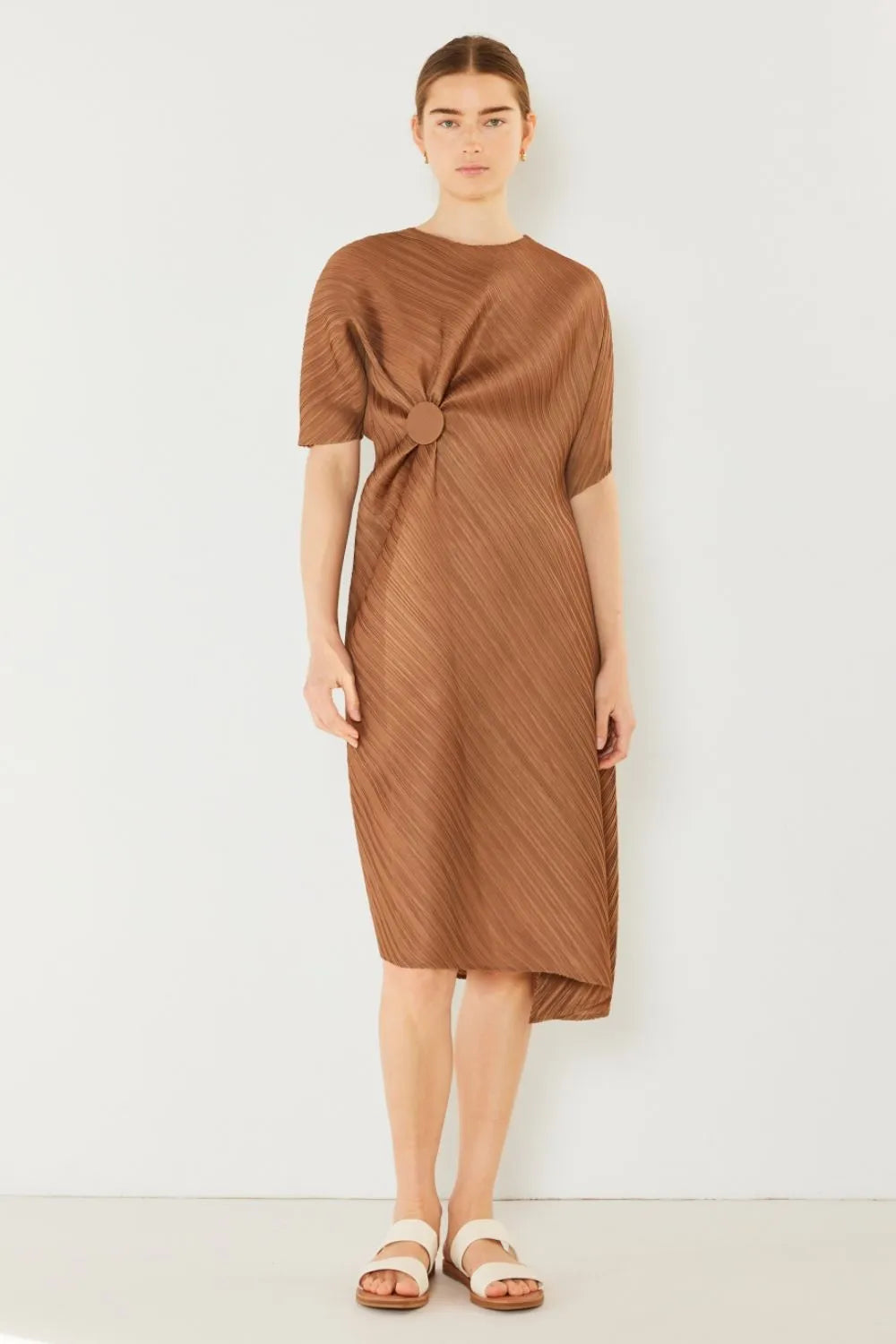 Woman wearing a brown dress with a knot detail on a white background: NEWYORKLISTED STYLE COLLECTION