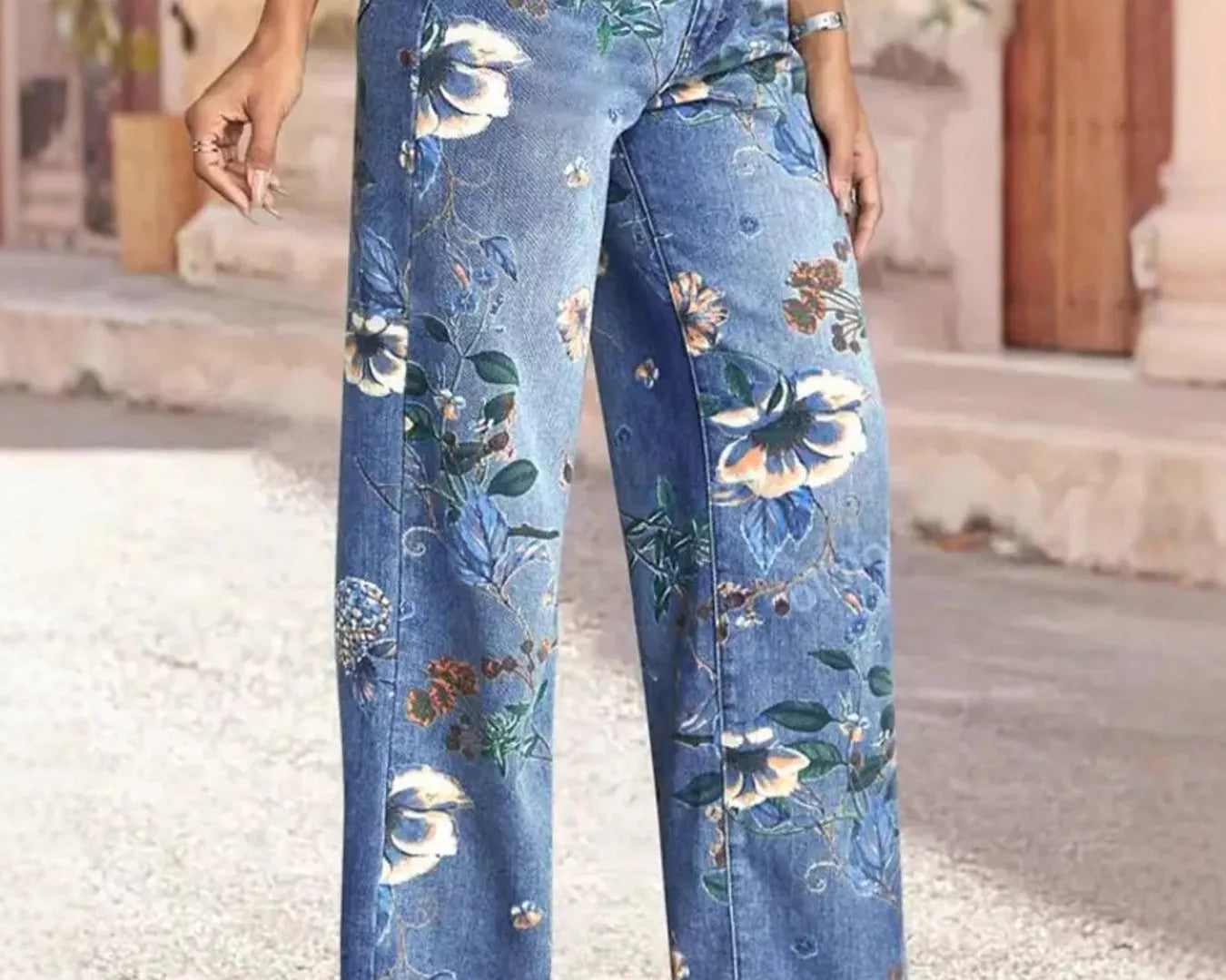 NEWYORKLISTED STYLE COLLECTION: Person wearing floral-patterned blue jeans standing on a stone pavement.