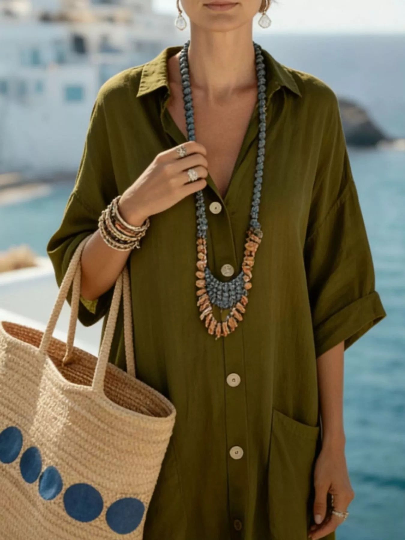 NEWYORKLISTED STYLE COLLECTION: Woman in an olive green dress holding a woven bag with a scenic background