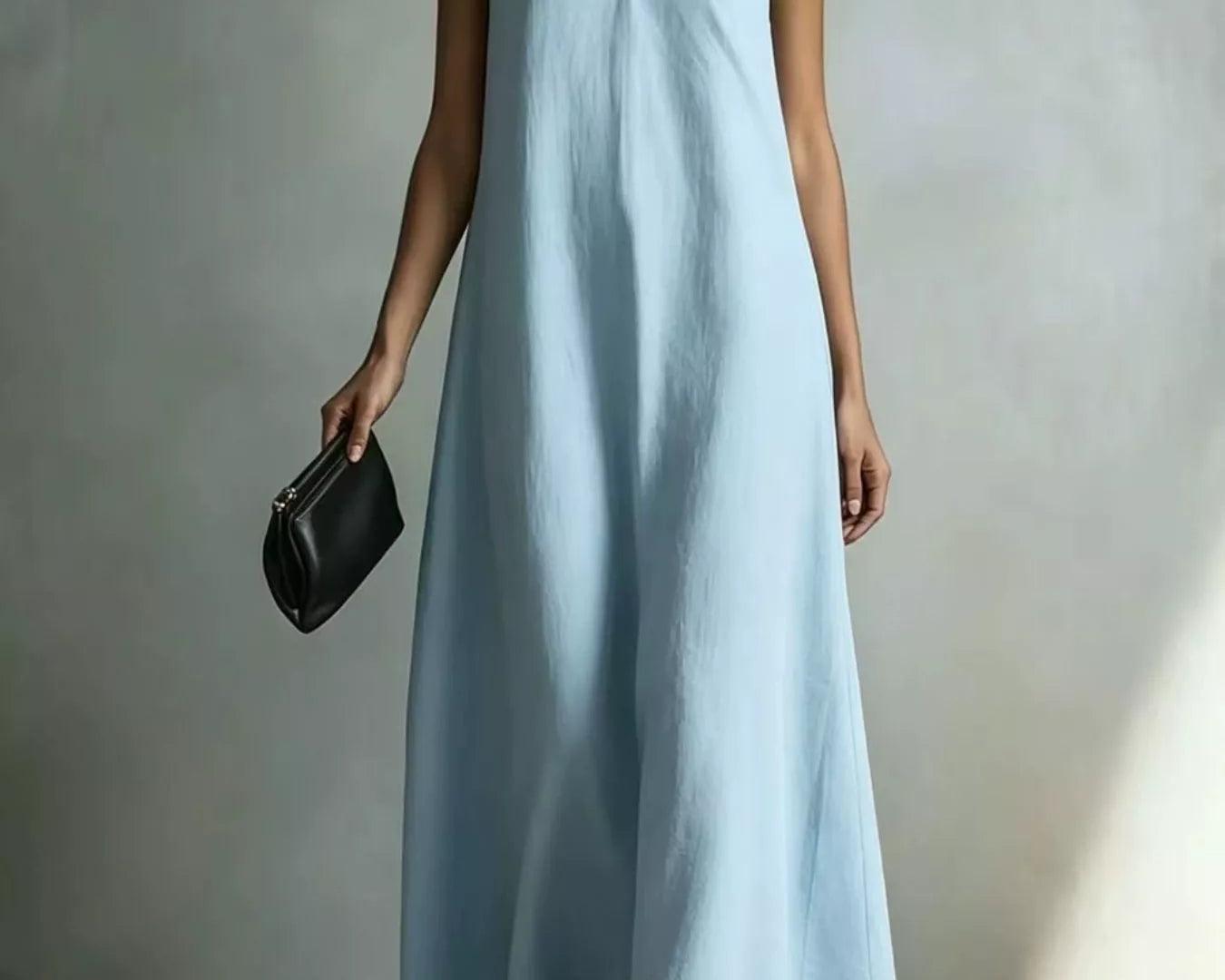 NEWYORKLISTED STYLE COLLECTION: A woman models a sleeveless light blue maxi dress with a V-neckline, holding a small black clutch bag against a neutral gray studio backdrop.
