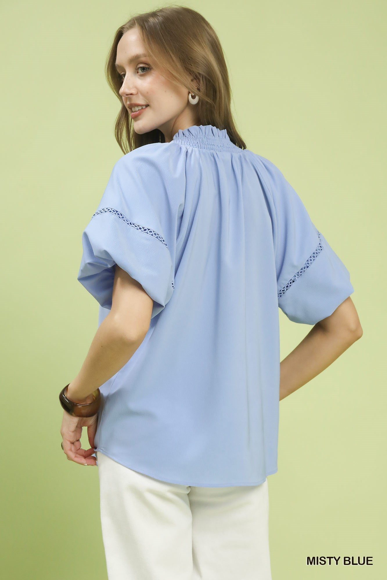 NEWYORKLISTED STYLE COLLECTION: Woman wearing a light blue blouse with embroidery on a light green background