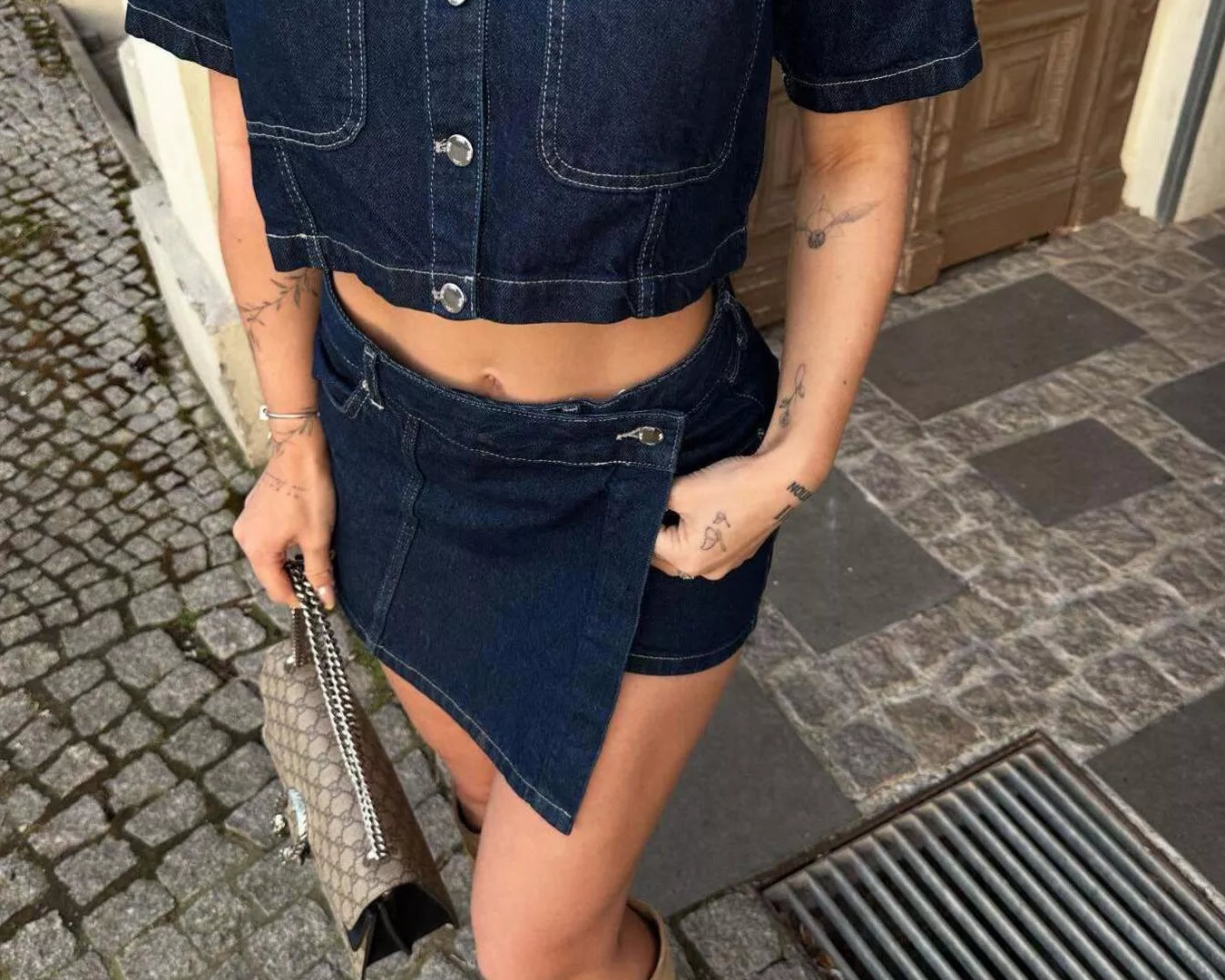 NEWYORKLISTED STYLE COLLECTION: Person wearing a denim outfit with a cropped shirt and shorts, standing on a street.