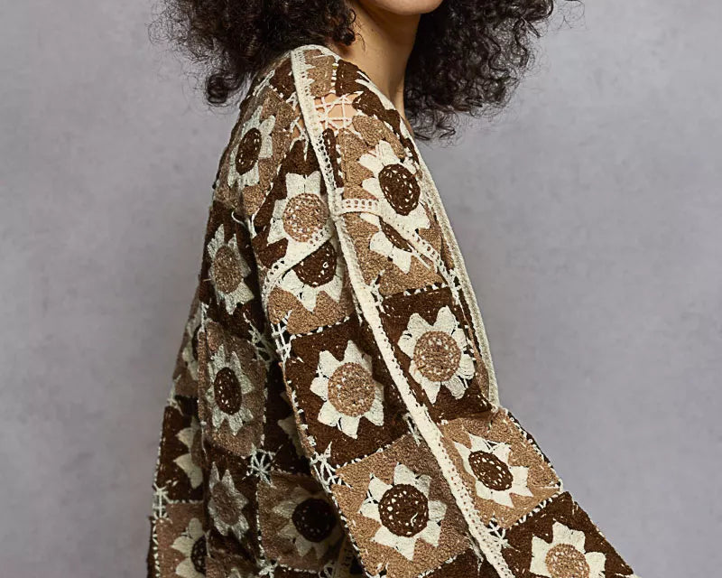NEWYORKLISTED STYLE COLLECTION: Woman wearing a patterned brown and beige shawl against a gray background