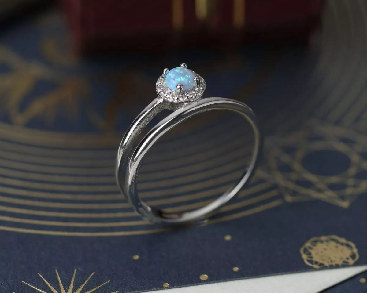 NYLD Glamour Collection by NEWYORKLISTED: Silver ring with a blue gemstone on a decorative surface