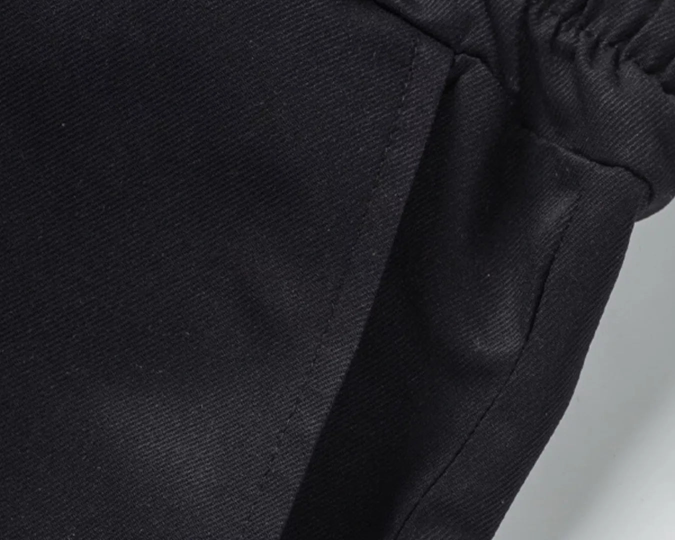 NEWYORKLISTED ATLAS MEN'S COLLECTION: Close-up of black pants with an elastic waistband on a light gray background