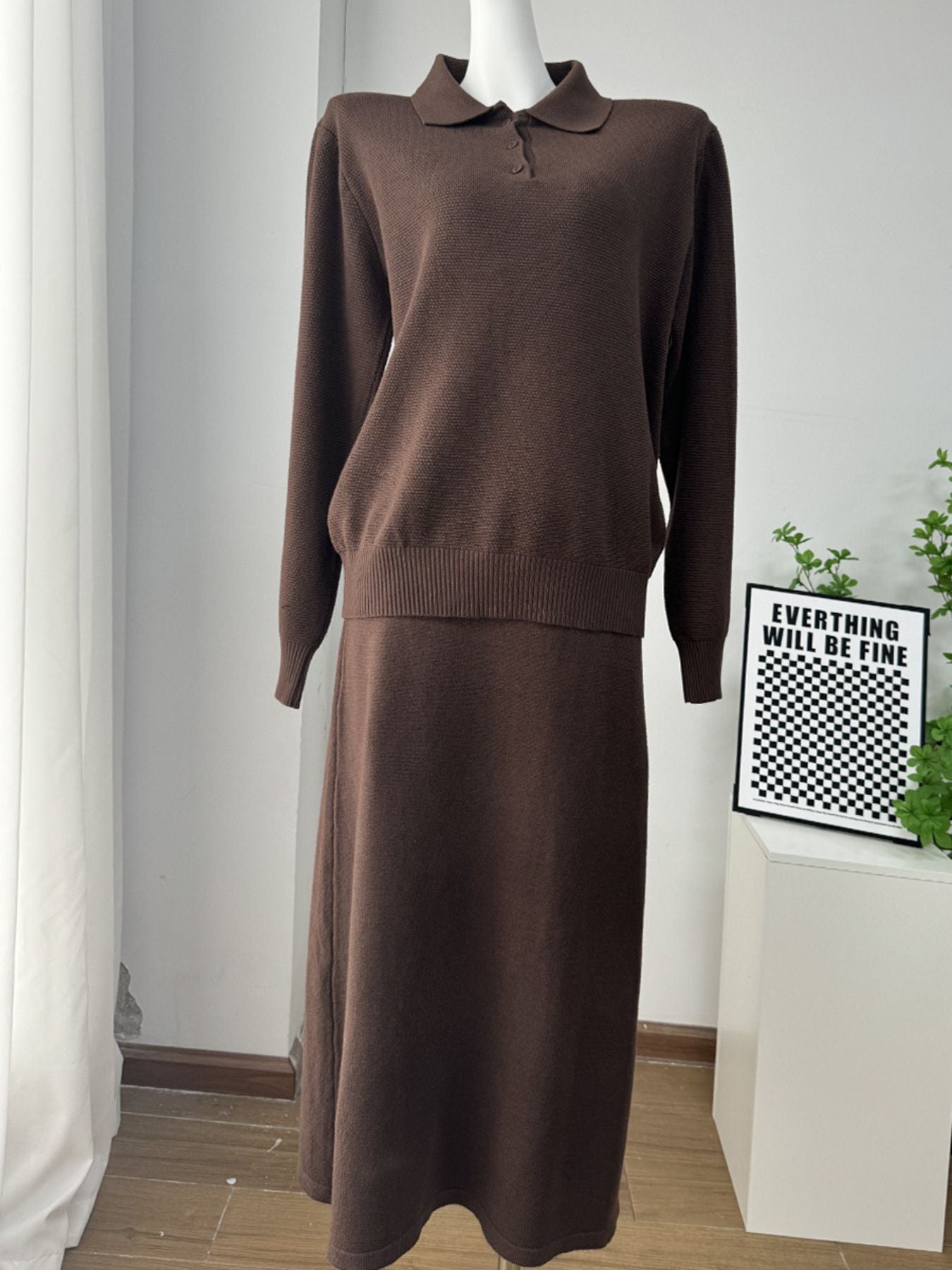 NEWYORKLISTED Comfort Collection: Brown two-piece outfit on a mannequin against a white wall with a framed quote.