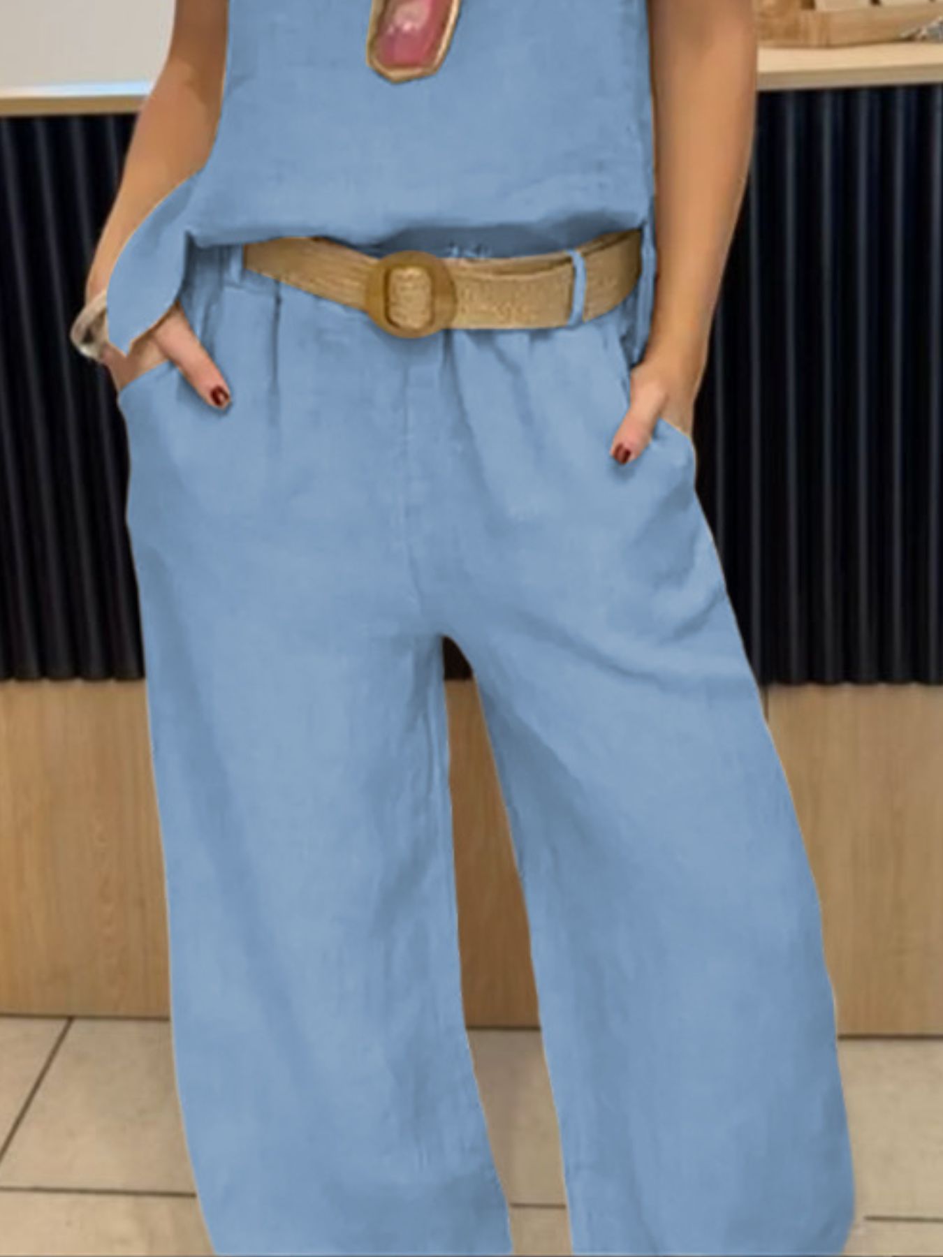 NEWYORKLISTED COMFORT COLLECTION: Person wearing a blue jumpsuit with a brown belt in an indoor setting