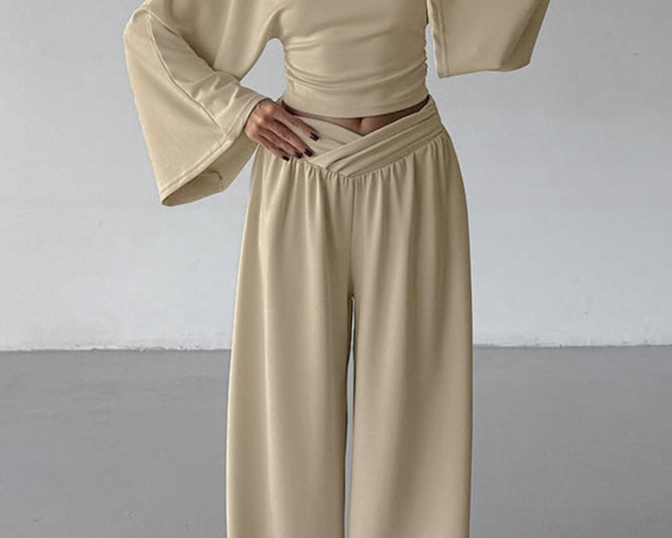 NEWYORKLISTED STYLE COLLECTION: Person wearing a beige outfit with wide sleeves and high-waisted pants against a plain background
