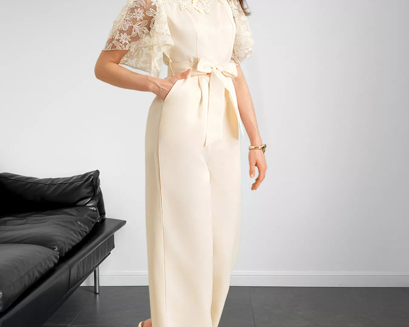 NEWYORKLISTED STYLE COLLECTION: Woman wearing a cream-colored dress with lace sleeves in a minimalistic room.
