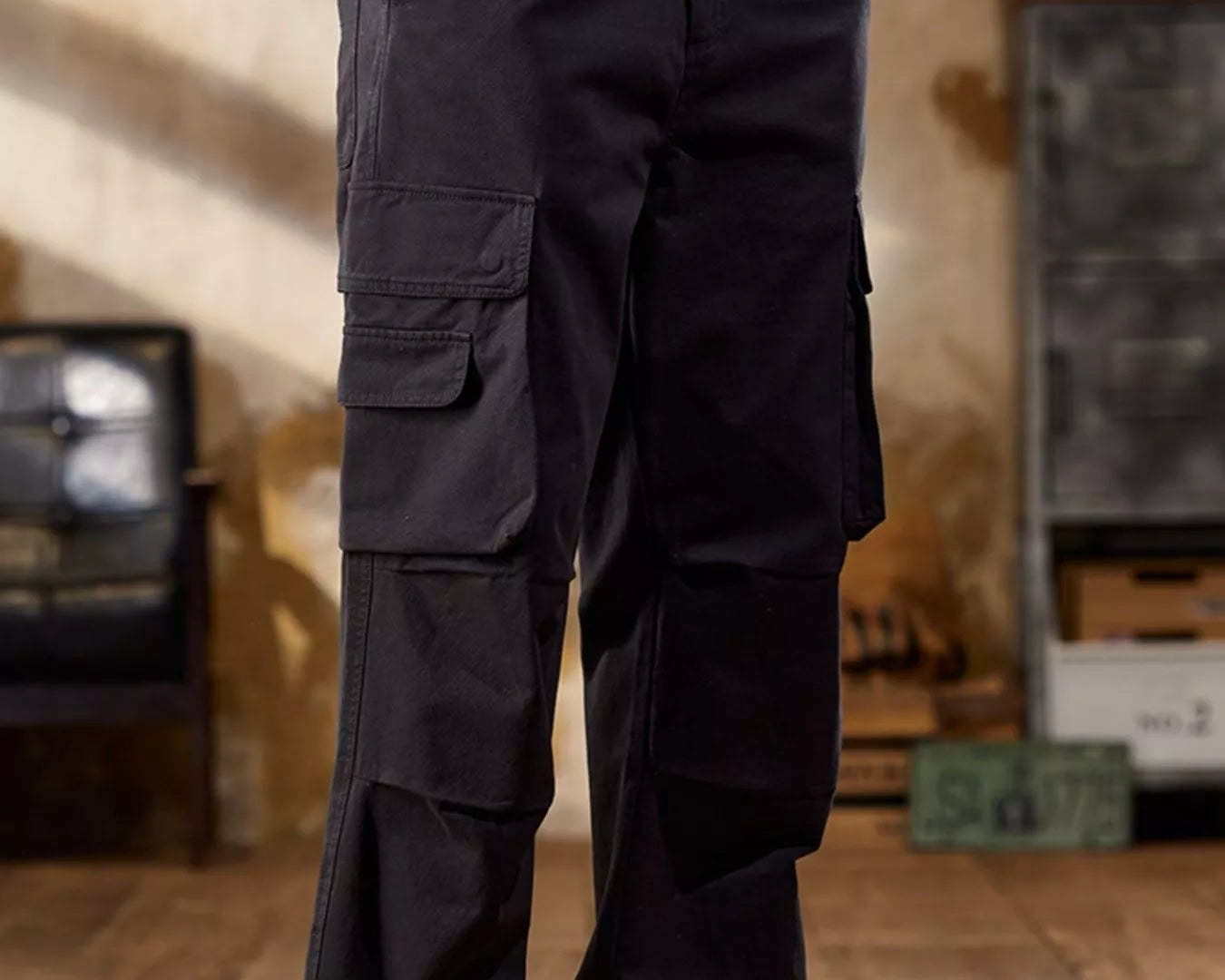 NEWYORKLISTED ATALS MEN's COLLECTION: Person wearing dark cargo pants with multiple pockets in an indoor setting.