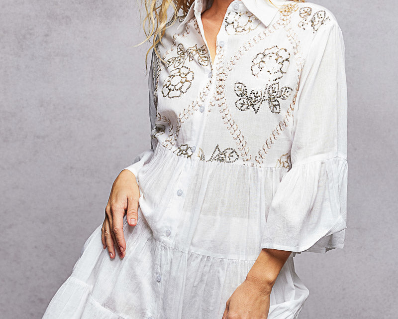 NEWYORKLISTED STYLE COLLECTION: Woman wearing a white embroidered dress against a gray background