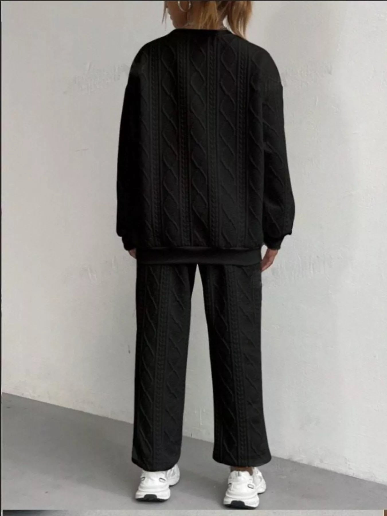NEWYORKLISTED COMFORT COLLECTION: Person wearing a black textured sweater and pants set against a plain background