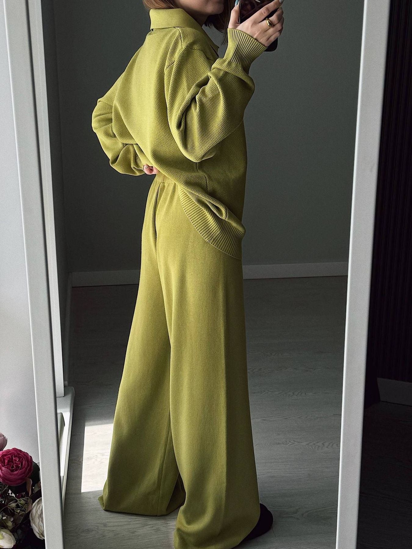 Person wearing a green knit outfit standing in front of a mirror.