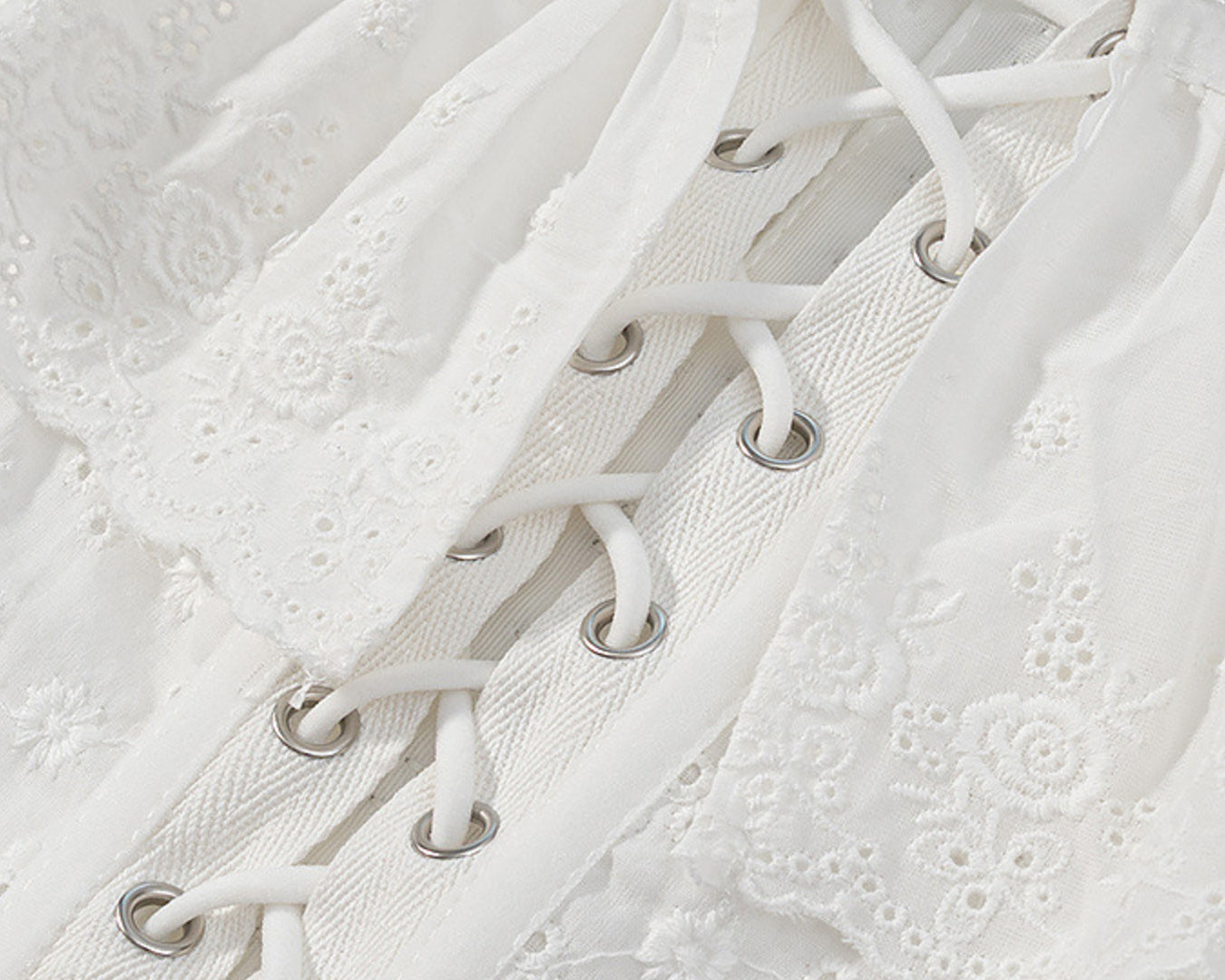 NEWYORKLISTED STYLE COLLECTION: Close-up of a white lace-up garment with intricate detailing.