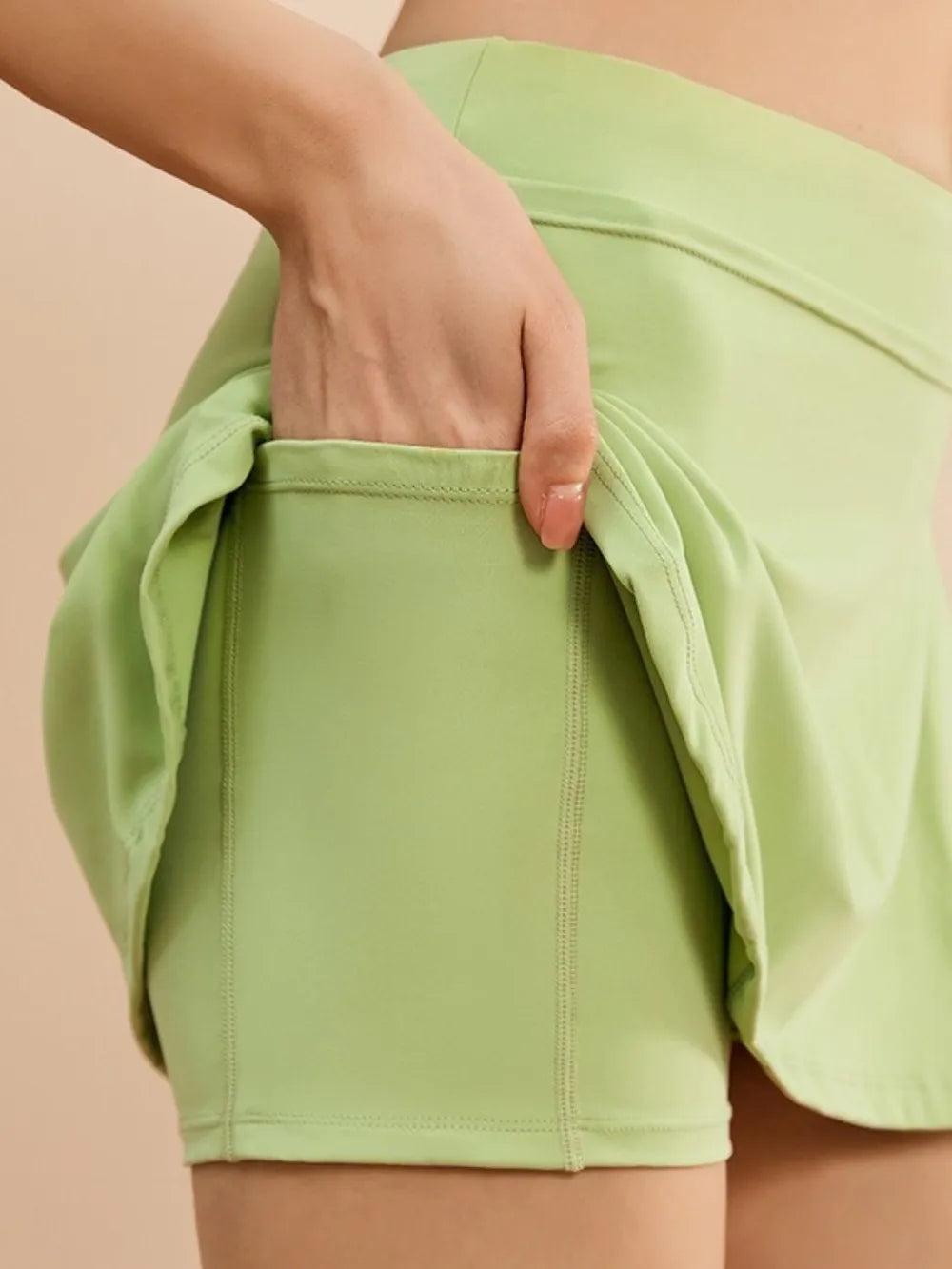 NEWYORKLISTED ACTIVEWEAR COLLECTION: Light green shorts being worn with a beige background