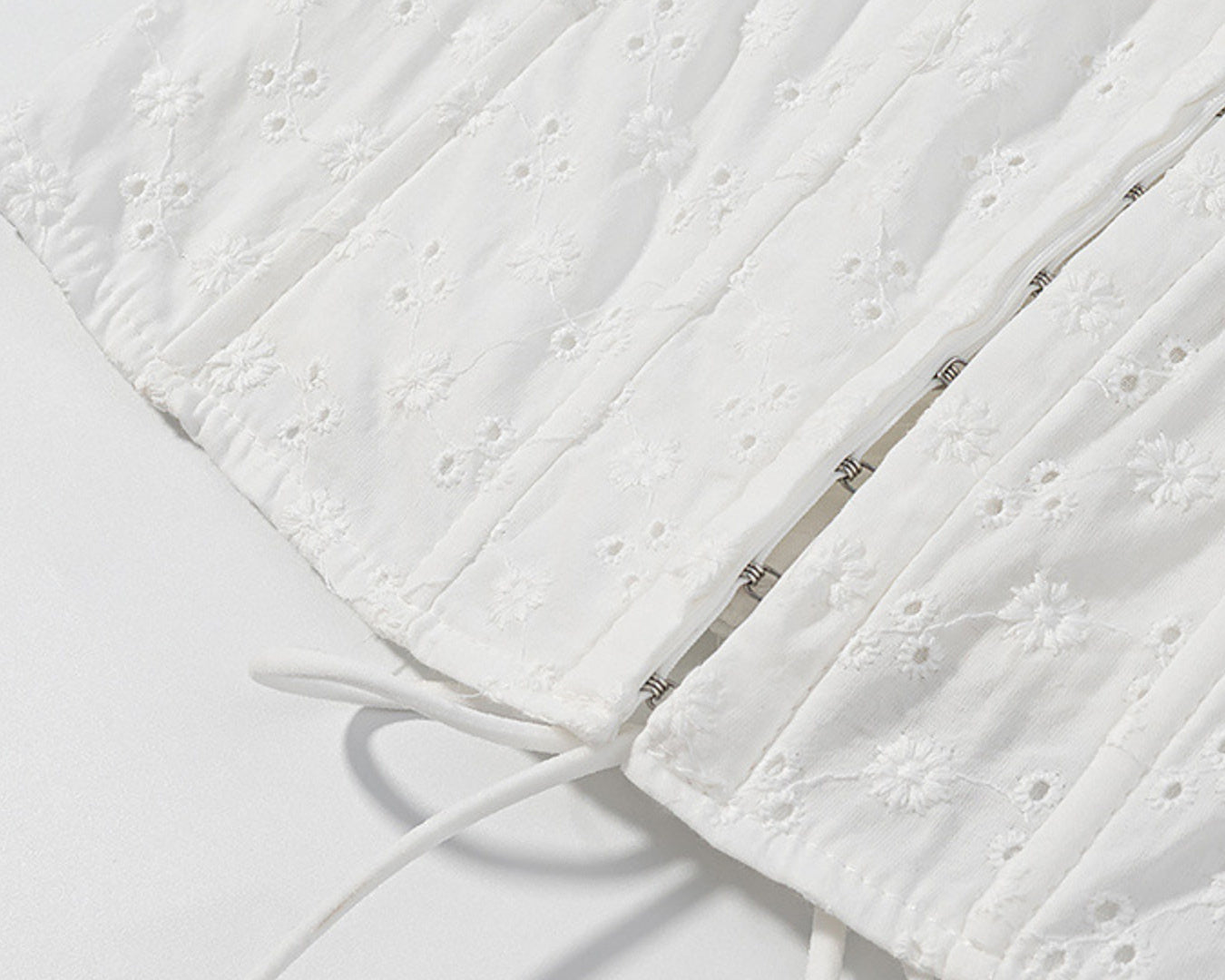 NEWYORKLISTED STYLE COLLECTION: Close-up of a textured white fabric with a zipper on a light gray background