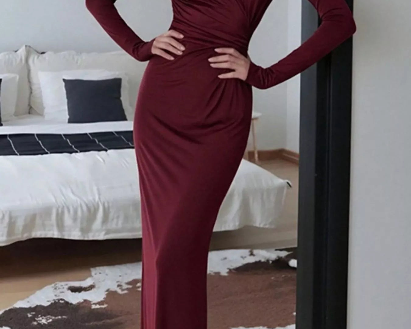 NEWYORKLISTED STYLE COLLECTION: Person wearing a burgundy dress standing in a bedroom.
