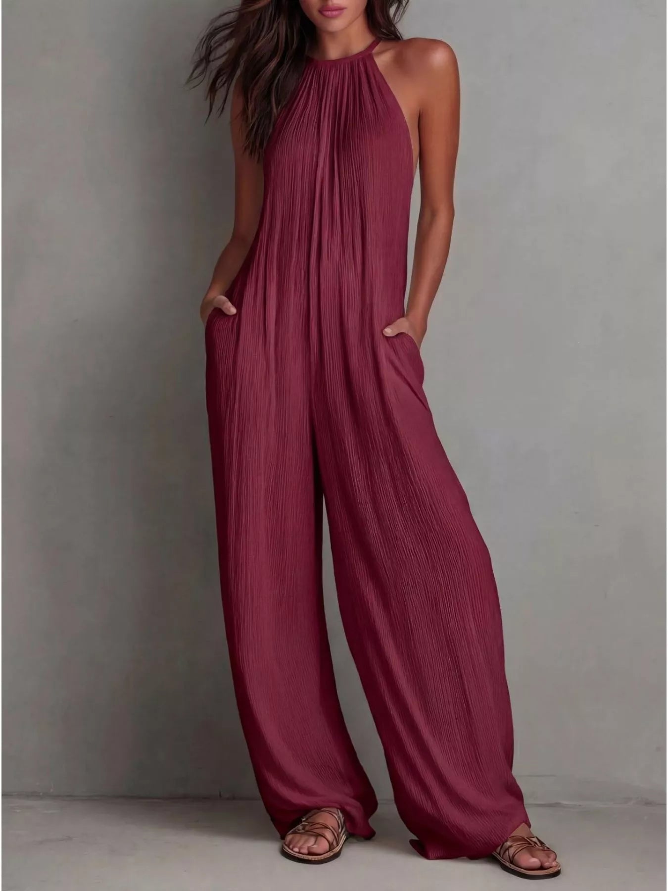NEWYORKLISTED STYLE COLLECTION: Woman wearing a burgundy jumpsuit against a gray background