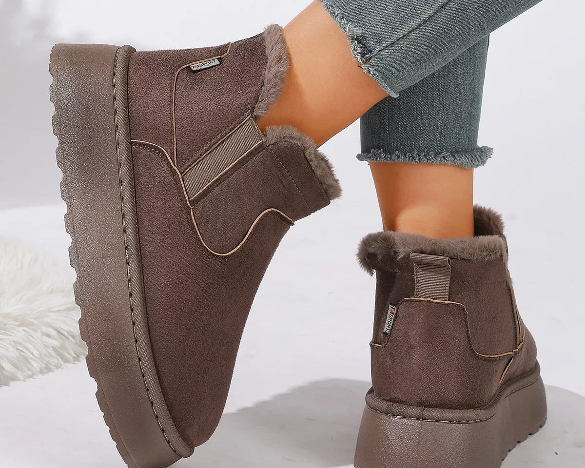 NEWYORKLISTED SHOE COLLECTION: A pair of women's brown suede-look ankle boots with plush faux-fur lining, shown on a model wearing gray frayed-hem jeans against a clean white background.