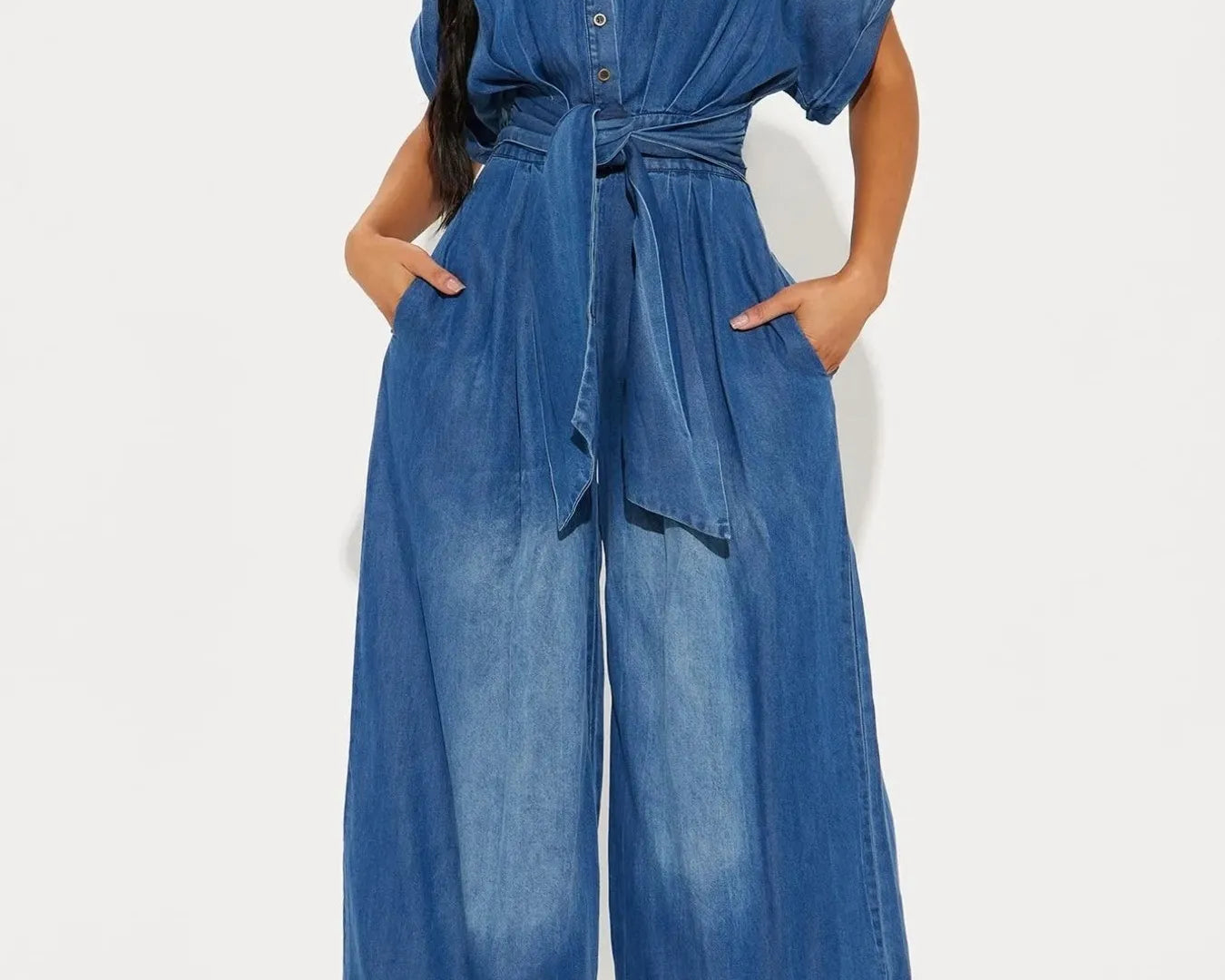 NEWYORKLISTED STYLE COLLECTION: Woman wearing a blue denim jumpsuit on a white background