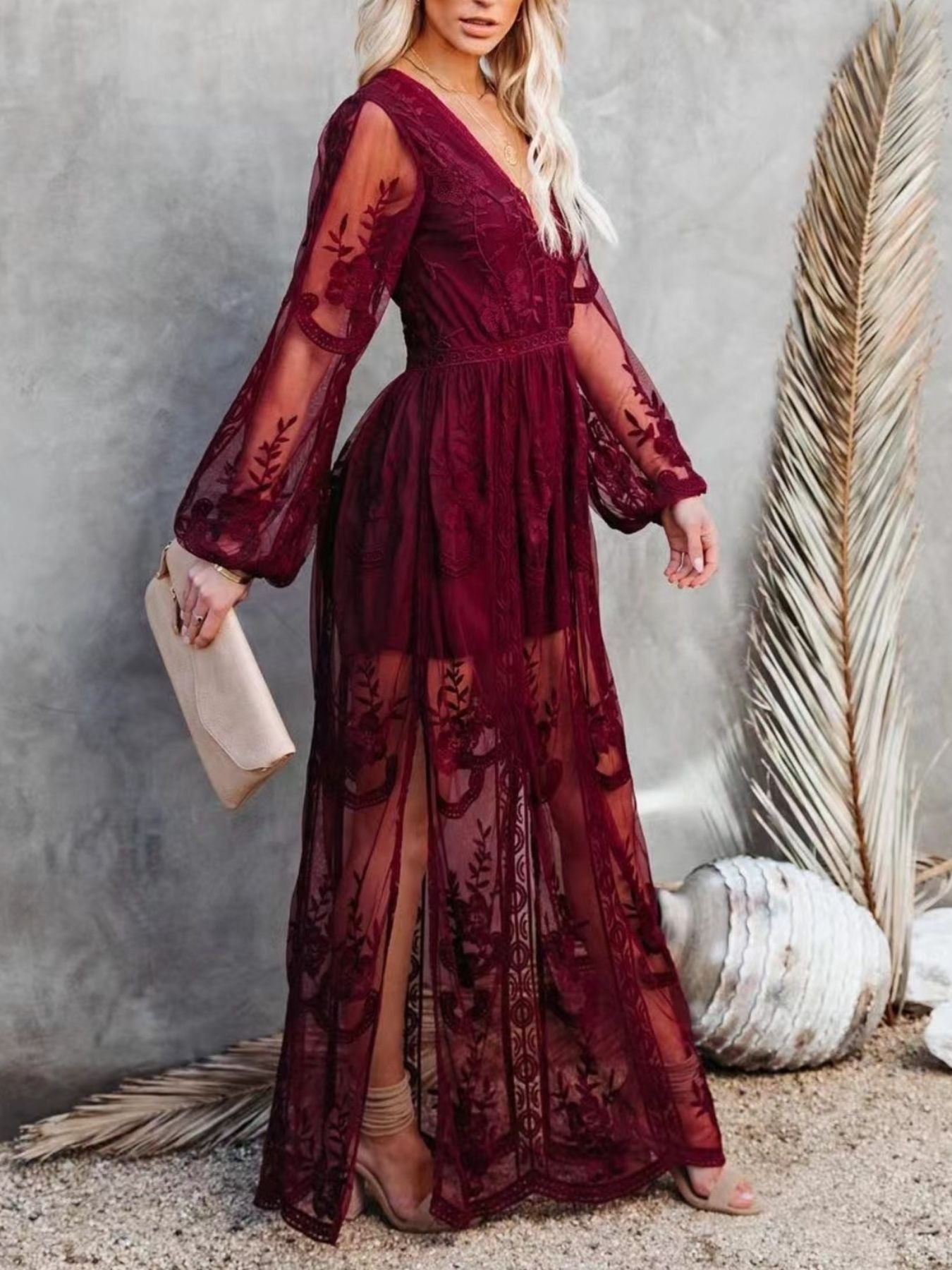 NEWYORKLISTED STYLE COLLECTION: Woman wearing a burgundy lace dress with sheer sleeves against a neutral background