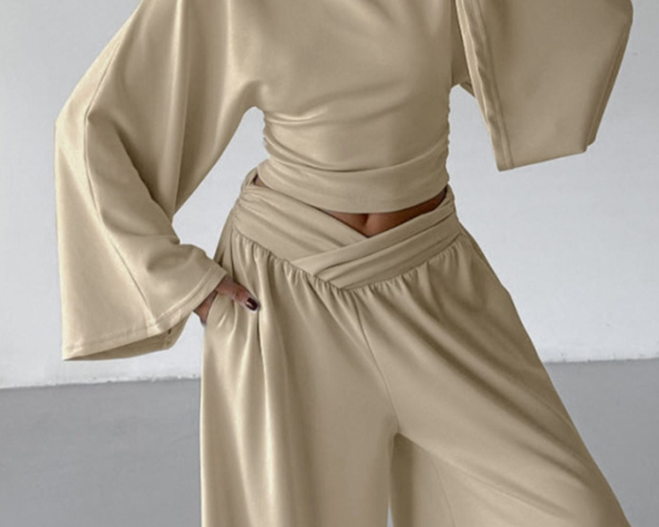 NEWYORKLISTED STYLE COLLECTION: Person wearing a beige outfit with wide sleeves and high-waisted pants against a plain background
