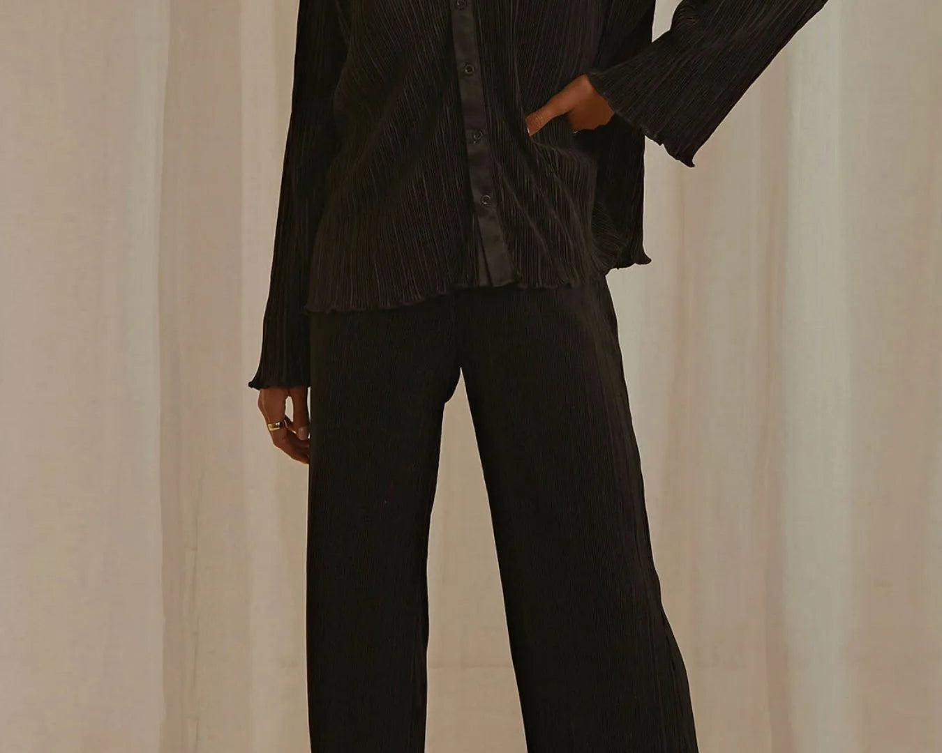 NEWYORKLISTED STYLE COLLECTION: Model wearing a black outfit with wide-leg pants against a neutral background