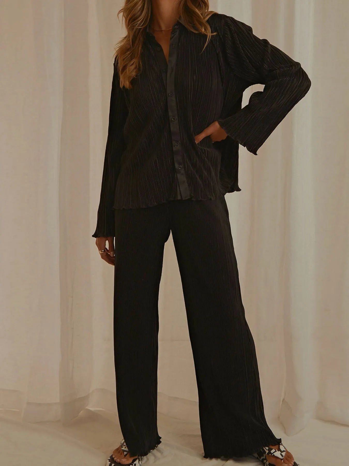 NEWYORKLISTED STYLE COLLECTION: Model wearing a black outfit with wide-leg pants against a neutral background