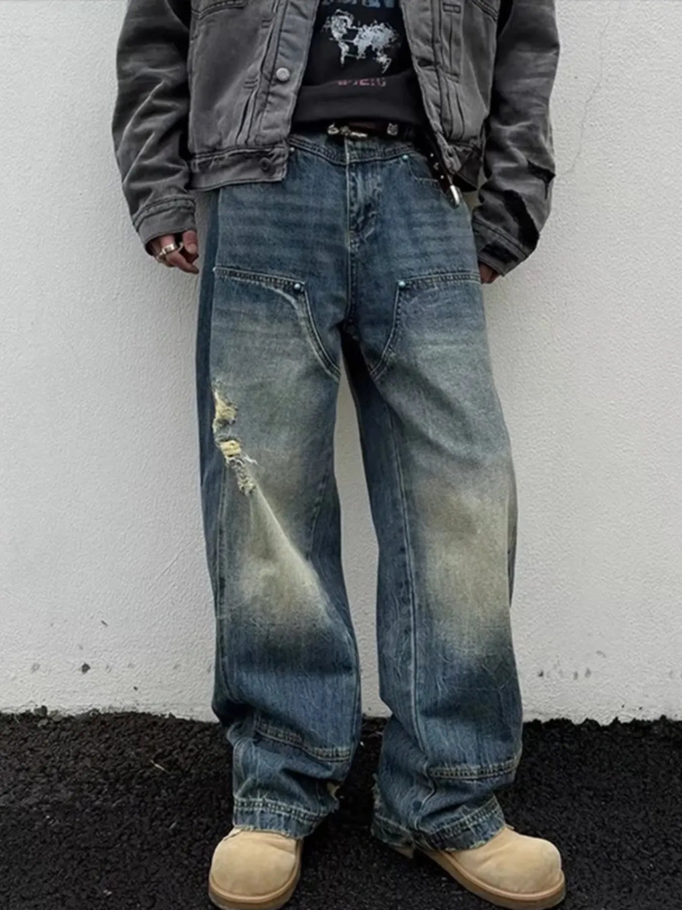 NEWYORKLISTED ATLAS MEN's COLLECTION: Person wearing distressed blue jeans and a dark jacket against a white wall.