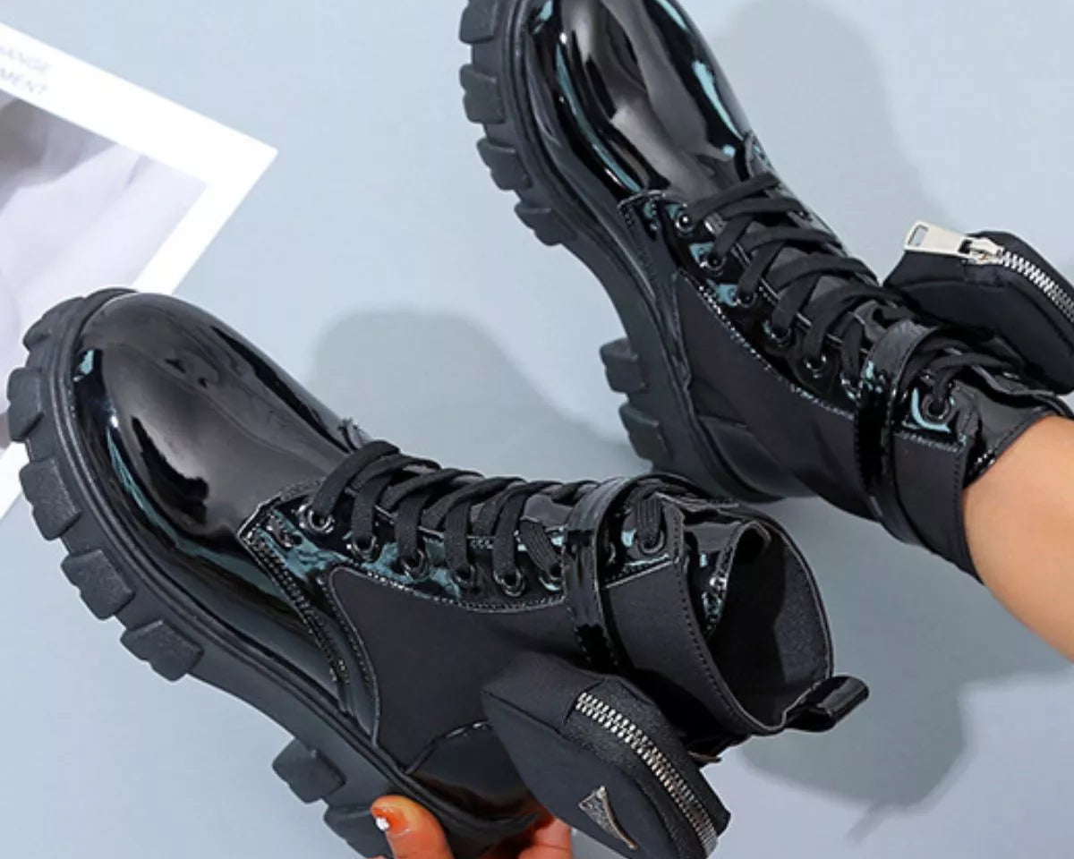 NEWYORKLISTED SHOE COLLECTION: Black high-top sneakers with chunky soles held by a hand on a light blue background