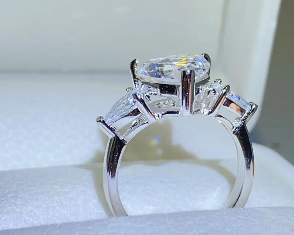 NYLD Glamour Collection By NEWYORKLISTED: Silver ring with a large central diamond and smaller side stones on a white background