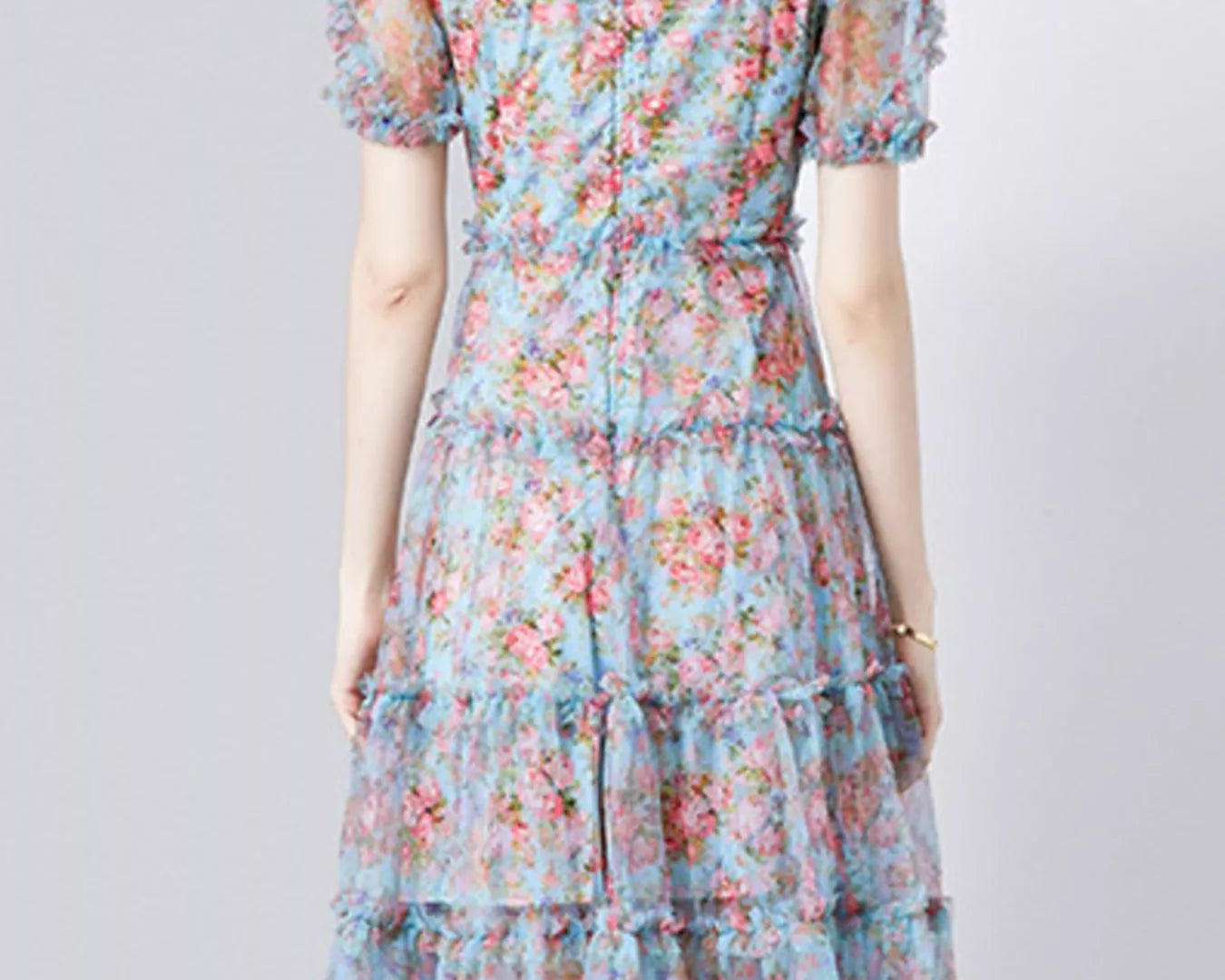 NEWYORKLISTED STYLE COLLECTION: Woman wearing a floral dress on a plain background